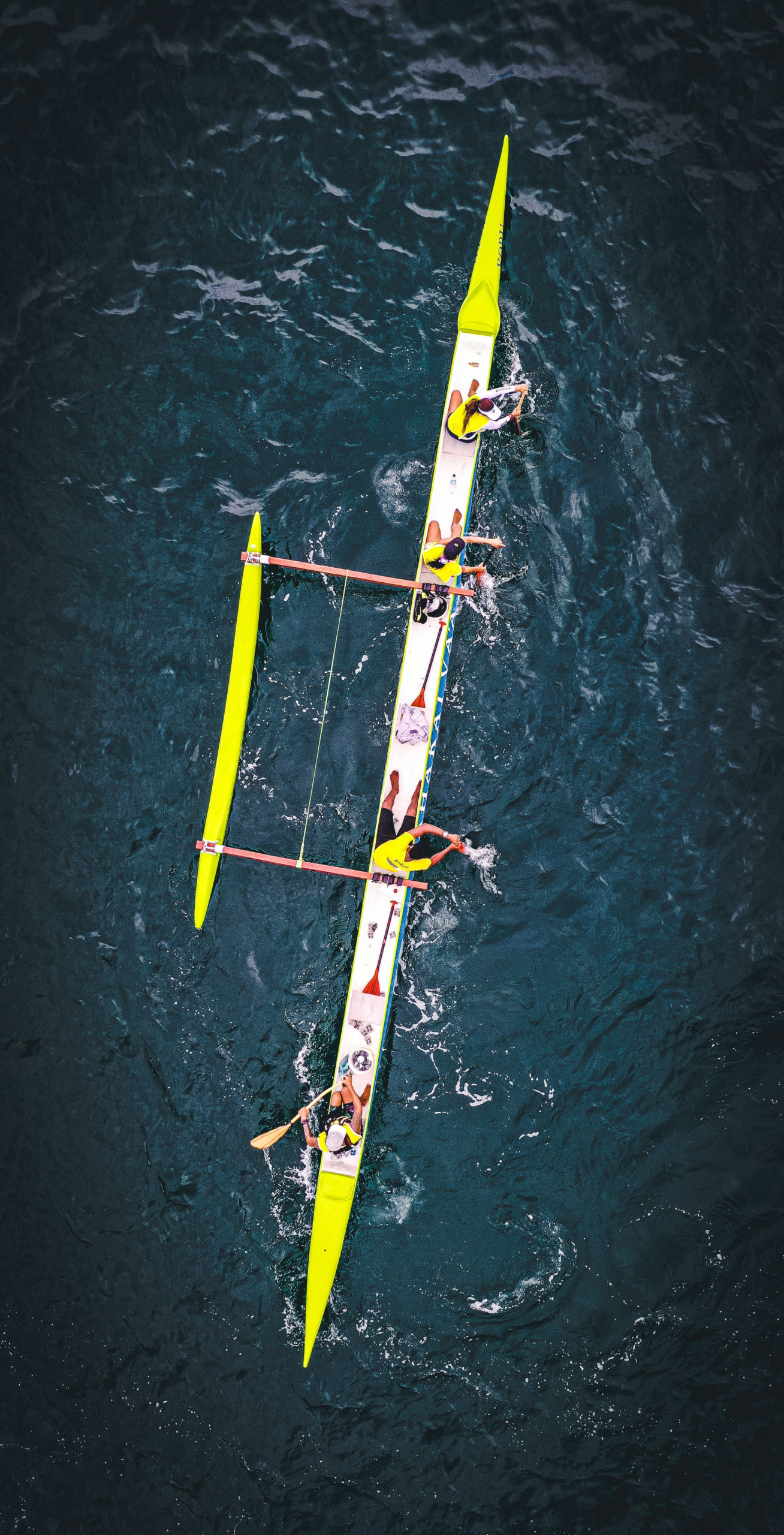 Team paddleboarding on open water aerial view