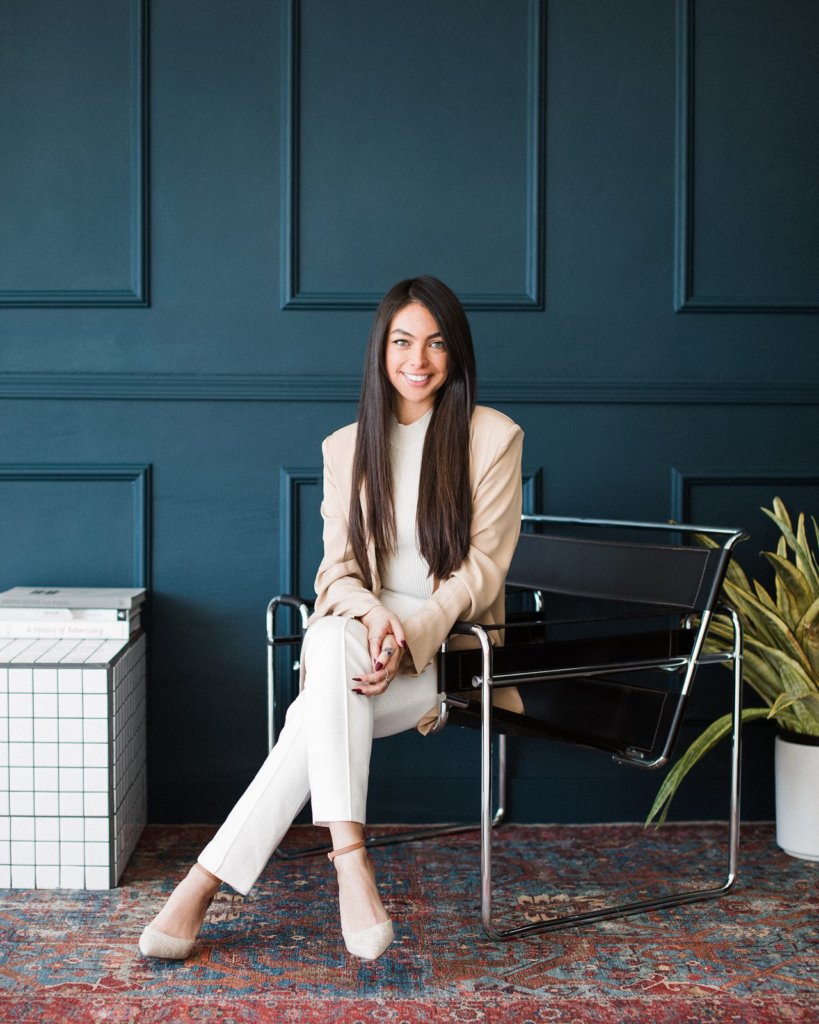 Sharissa Villanueva seated full-length against a teal panelled wall