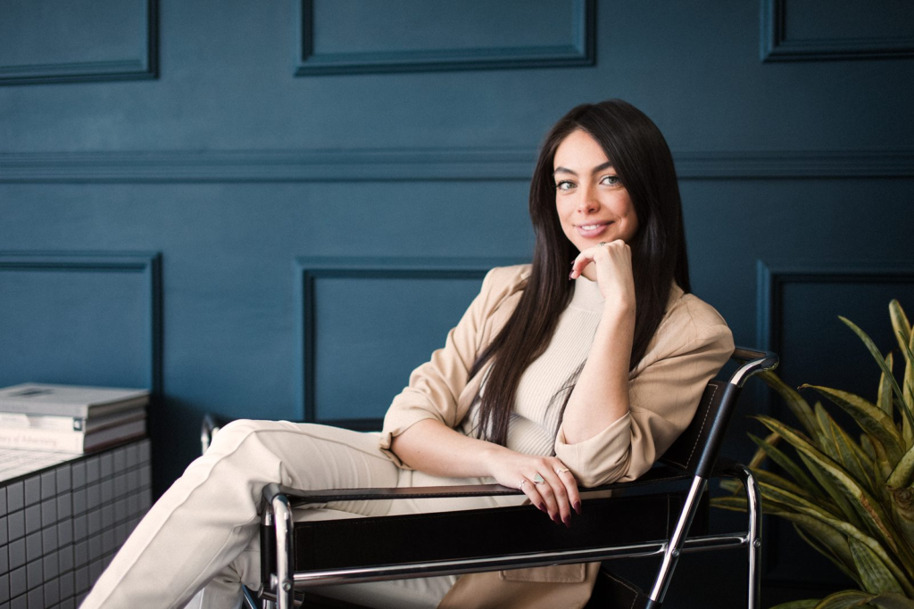 Sharissa Villanueva seated in a leather chair against a teal panelled wall