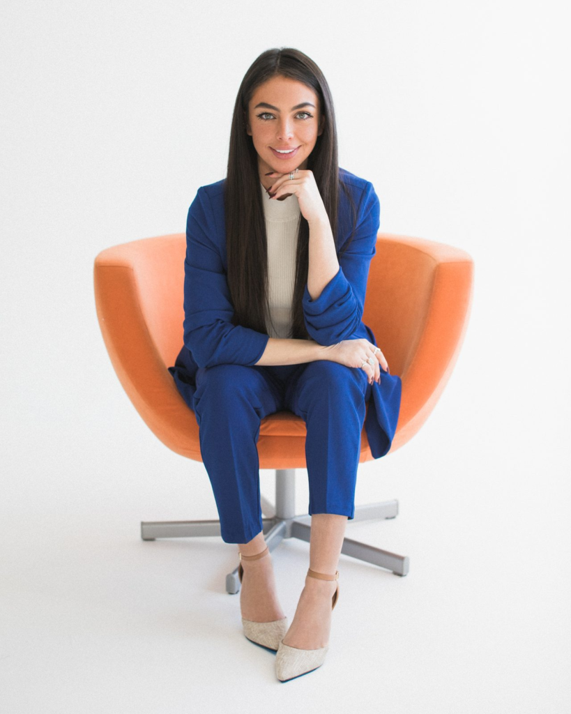 Sharissa Villanueva seated in an orange chair, chin resting on hand