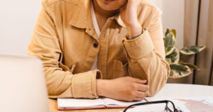 Person wearing beige jacket studying at desk